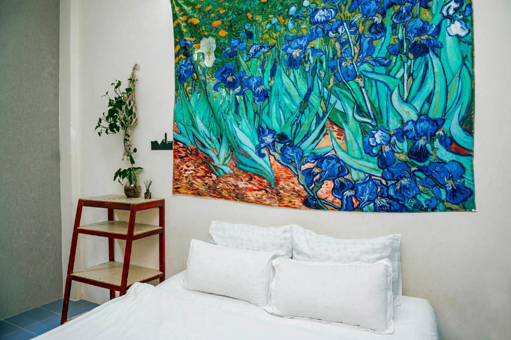 迪石Bụi Hostel - Bến Tàu Rạch Giá的一张床上墙上的画