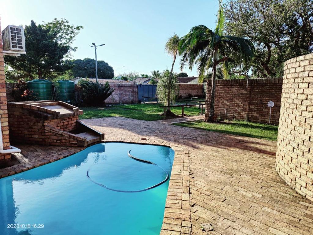 MtubatubaGREEN TREE的一座带砖墙的庭院中的蓝色游泳池