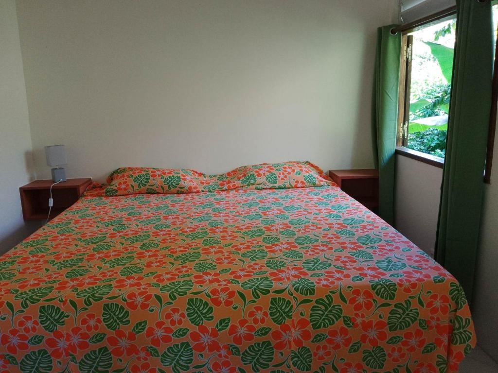 VaïareFare Mihimana的一间卧室配有一张带五颜六色的被子的床和窗户