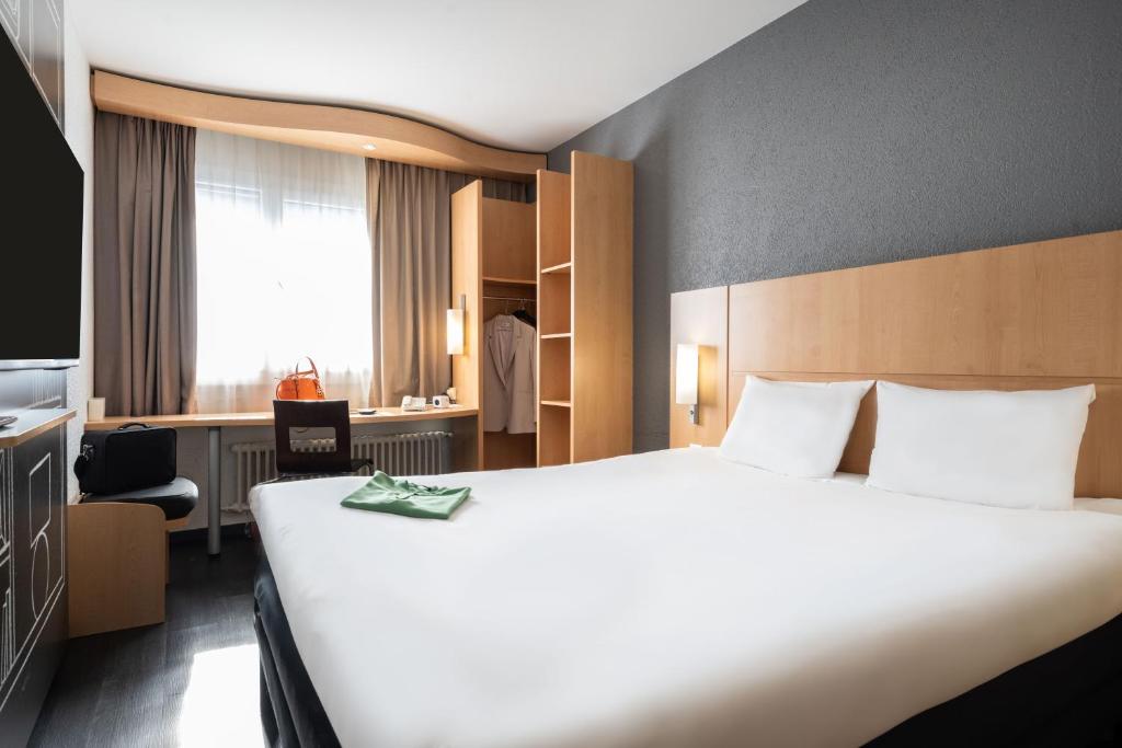 日内瓦日内瓦中心火车站宜必思酒店的酒店客房设有一张白色大床和椅子