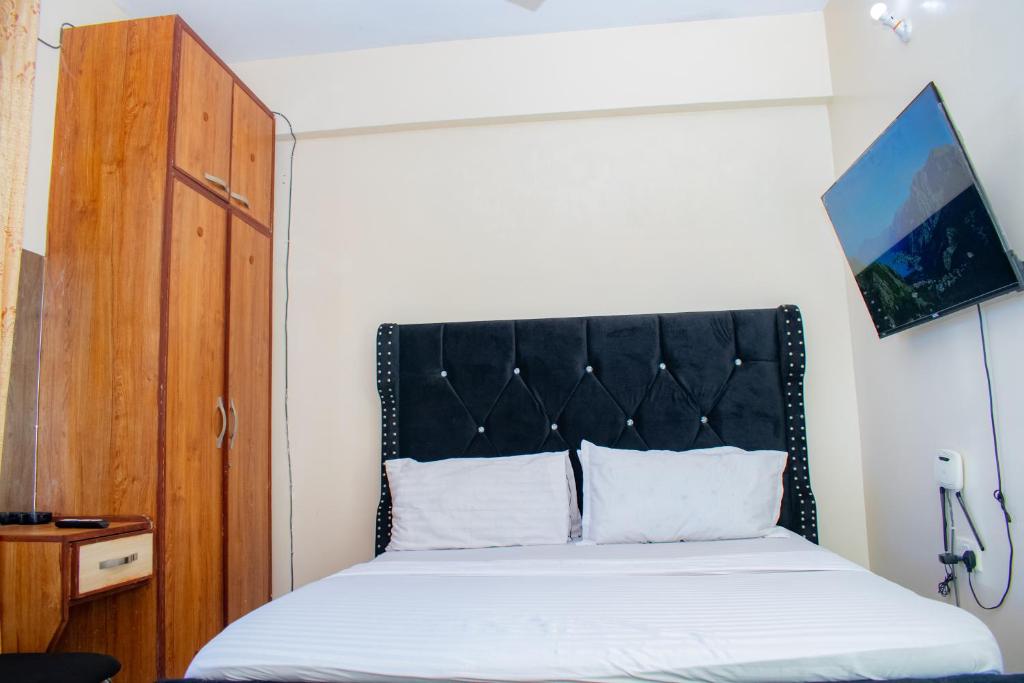 蒙巴萨The Nest Studio Apartment in Bamburi Mombasa的一张床上,上面有黑色床头板
