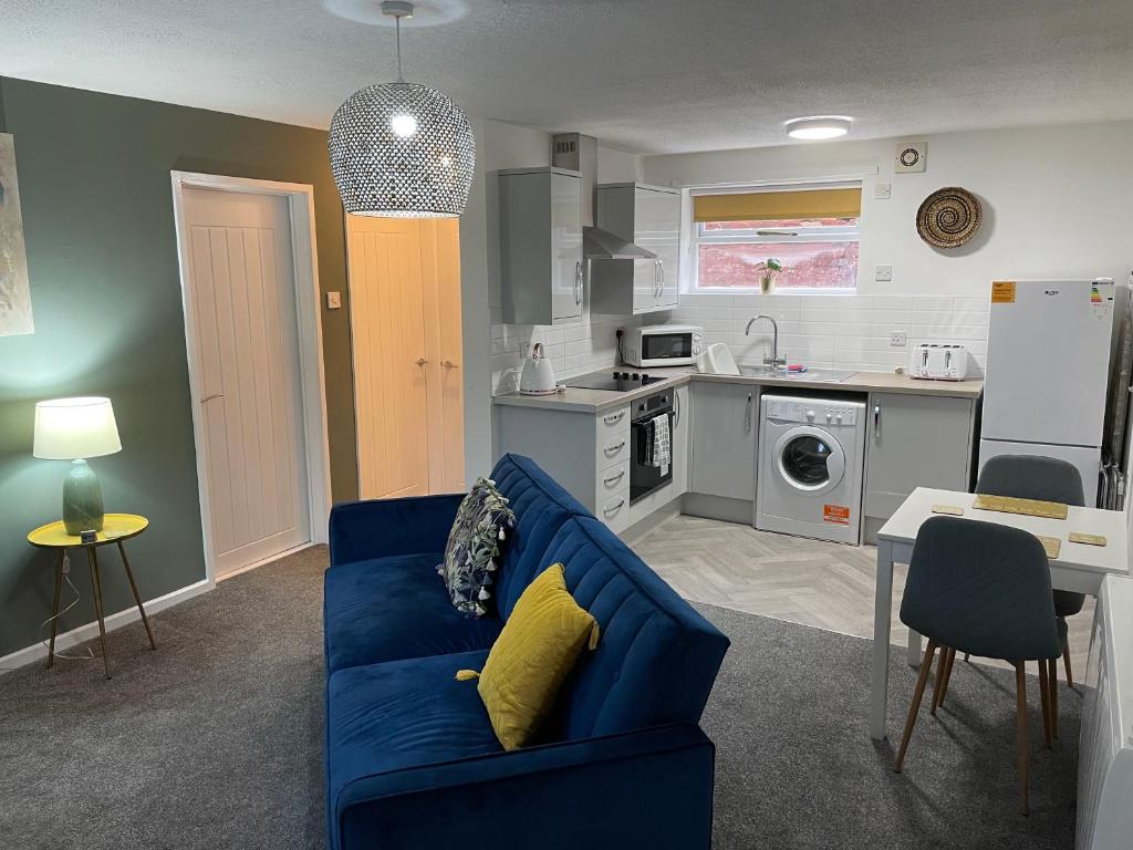 HednesfordThe Uxbridge Suite的一间带蓝色沙发的客厅和一间厨房