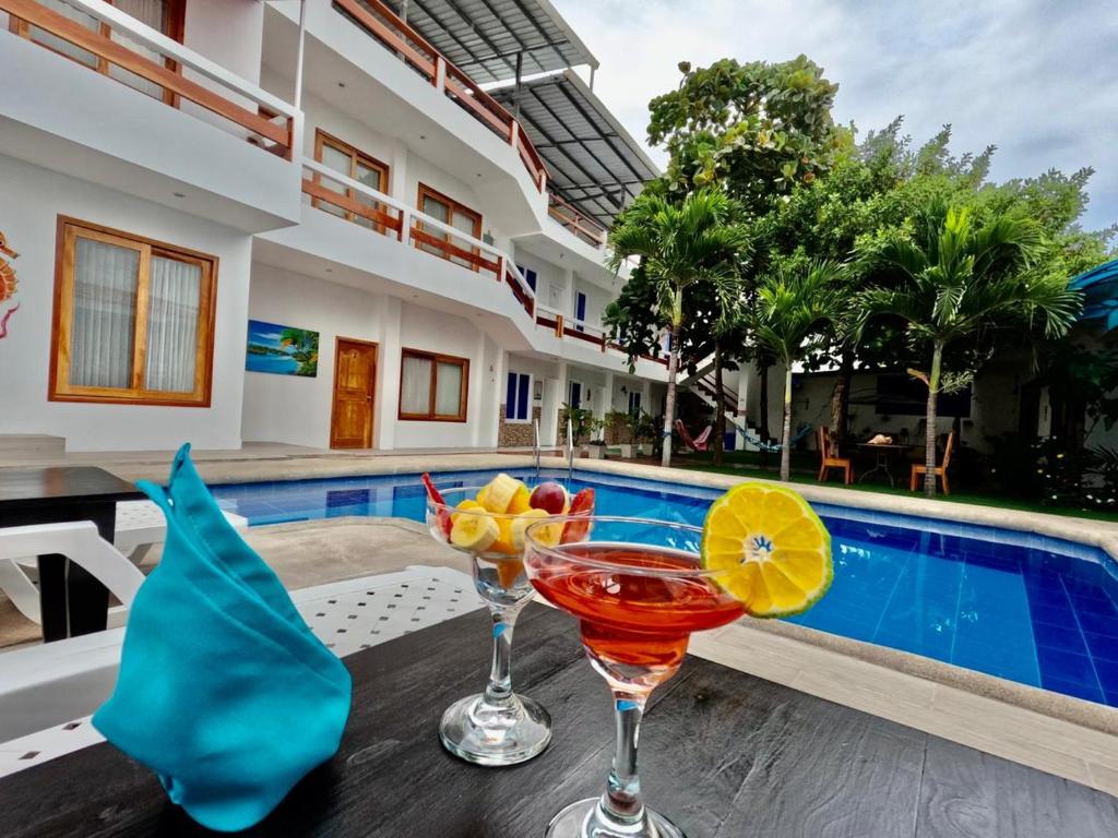 比亚米尔港Galápagos Isabela Hotel Loja的游泳池畔的餐桌上供应的2杯鸡尾酒