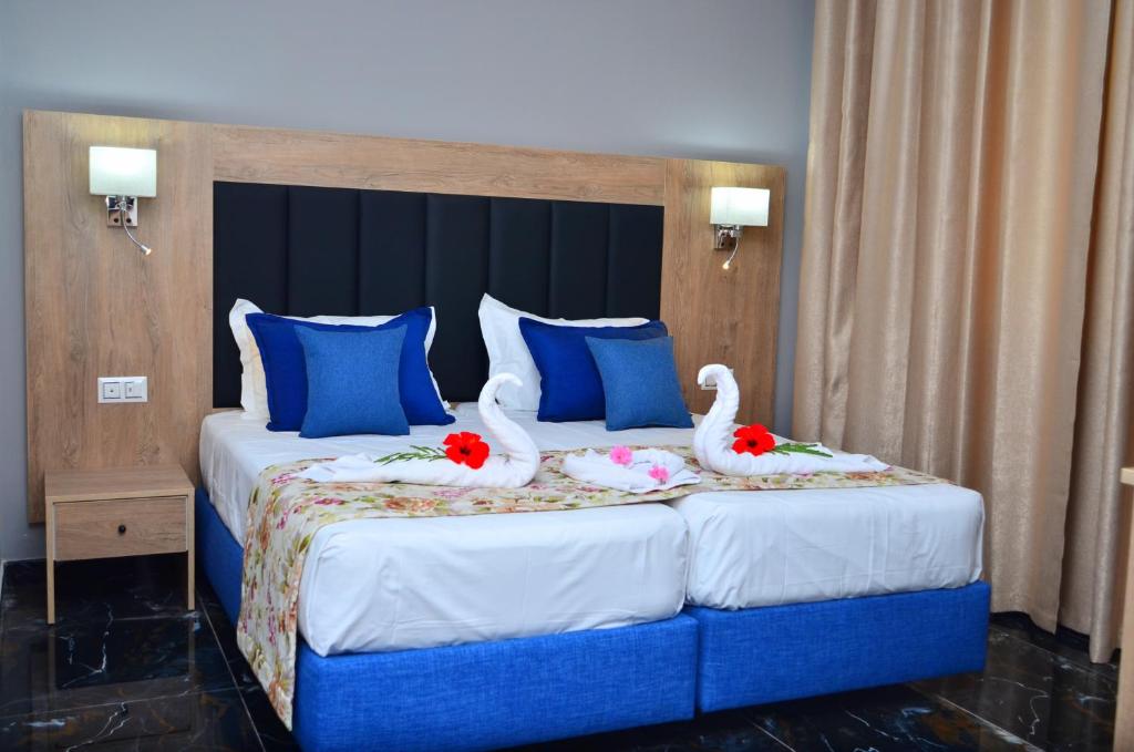 DjerbaHôtel Joya Paradise & SPA Djerba的两只天鹅坐在床上,床上有蓝色枕头