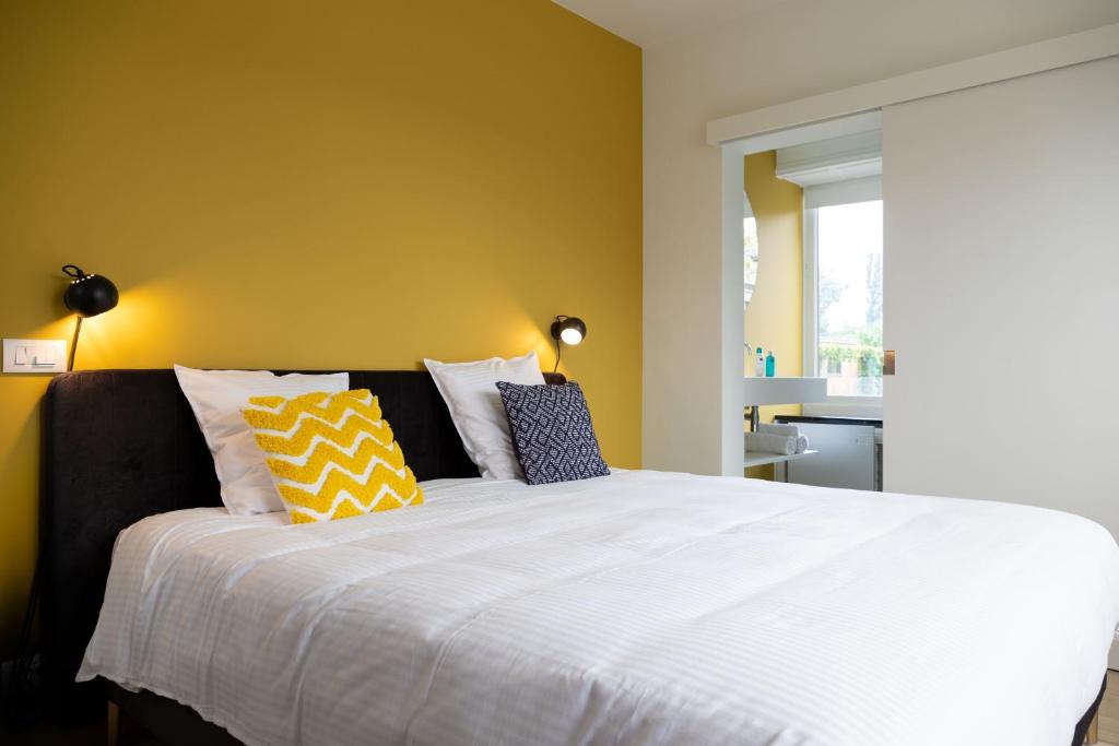 科特赖克Tuss的卧室设有一张白色大床和黄色的墙壁