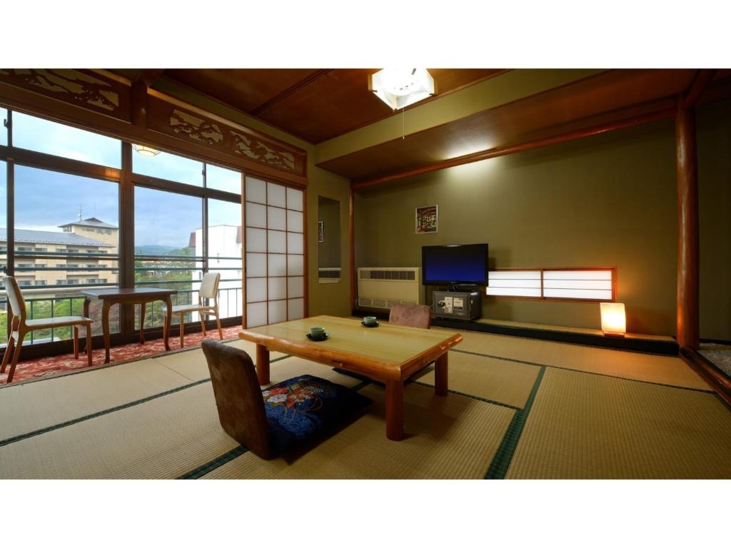 福岛Hotel Tenryukaku - Vacation STAY 16415v的一间带桌子的客厅和一个阳台