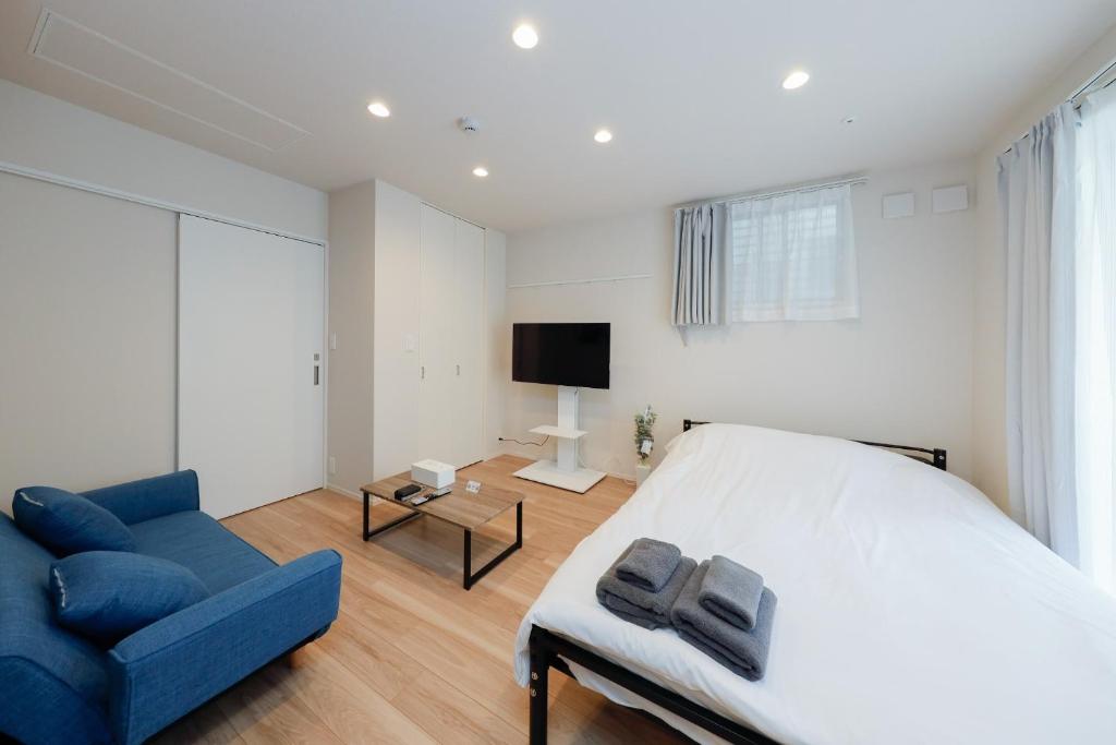 东京La Terrasse Higashikomagata - Vacation STAY 17380v的一间卧室配有一张床、一张蓝色的沙发和一台电视