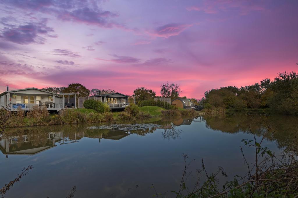 阿伦德尔Choller Lake Lodges - Primrose Cabin With Private Hot Tub的享有湖泊美景,设有房屋和日落美景