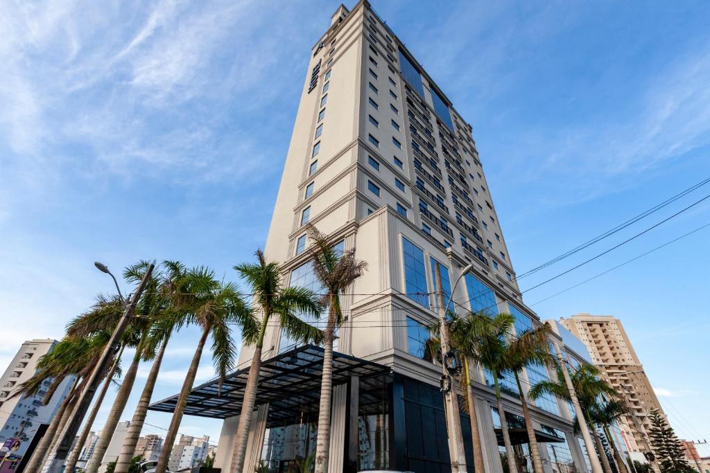 伊塔佩马Tri Hotel Premium Itapema的一座高大的建筑,前面有棕榈树