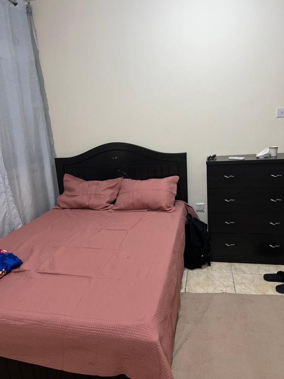 阿布扎比aldanah的一间卧室配有一张带粉色床单的床和梳妆台。