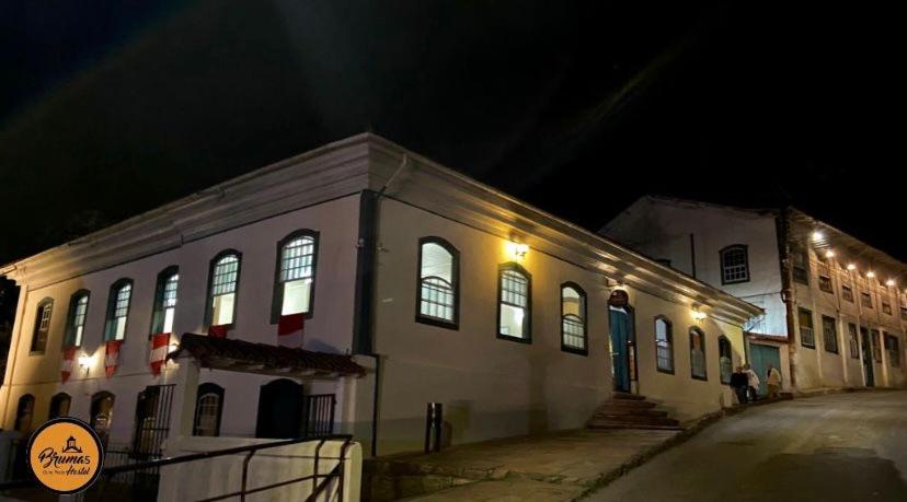 欧鲁普雷图Brumas Ouro Preto Hostel e Pousada的白色的建筑,晚上在街上灯火通明