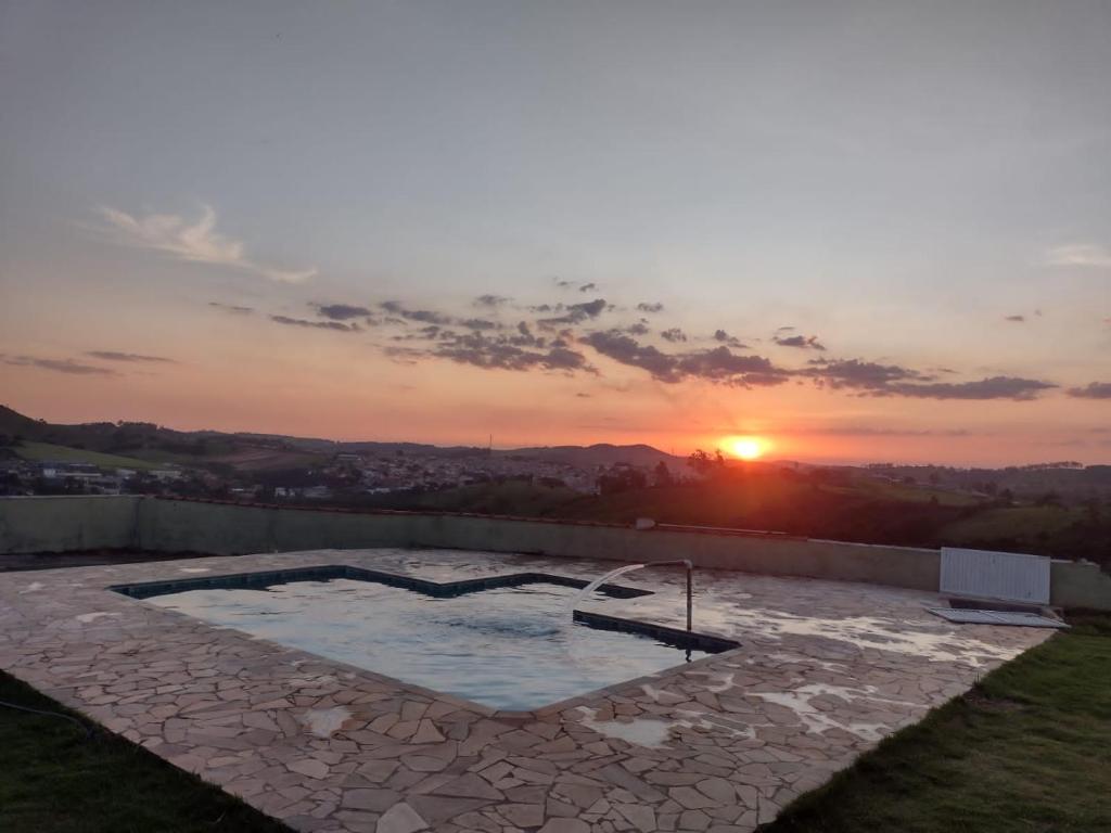皮尼亚尔齐纽Pedacinho do céu的游泳池的日落美景,设有石头露台