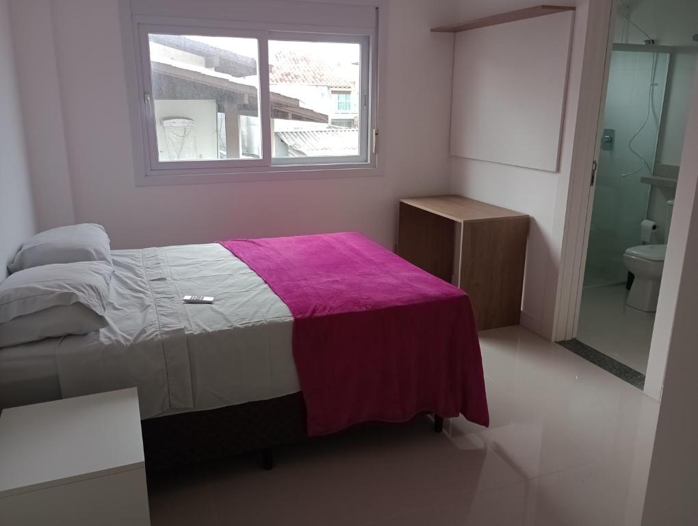 邦比尼亚斯Apto canto grande Bombinhas的一间卧室设有一张床、一个窗口和一间浴室