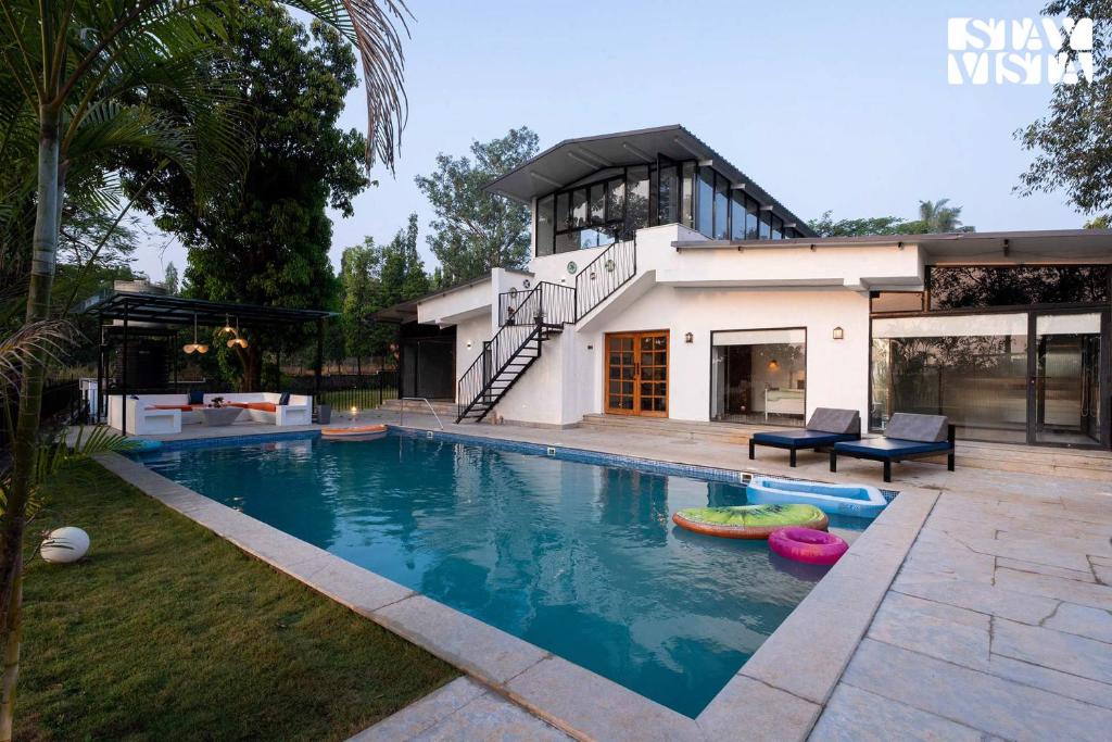 卡尔贾特StayVista's The Oasis - Serene Retreat with Private Pool, Lawn & Gazebo的房屋前的游泳池