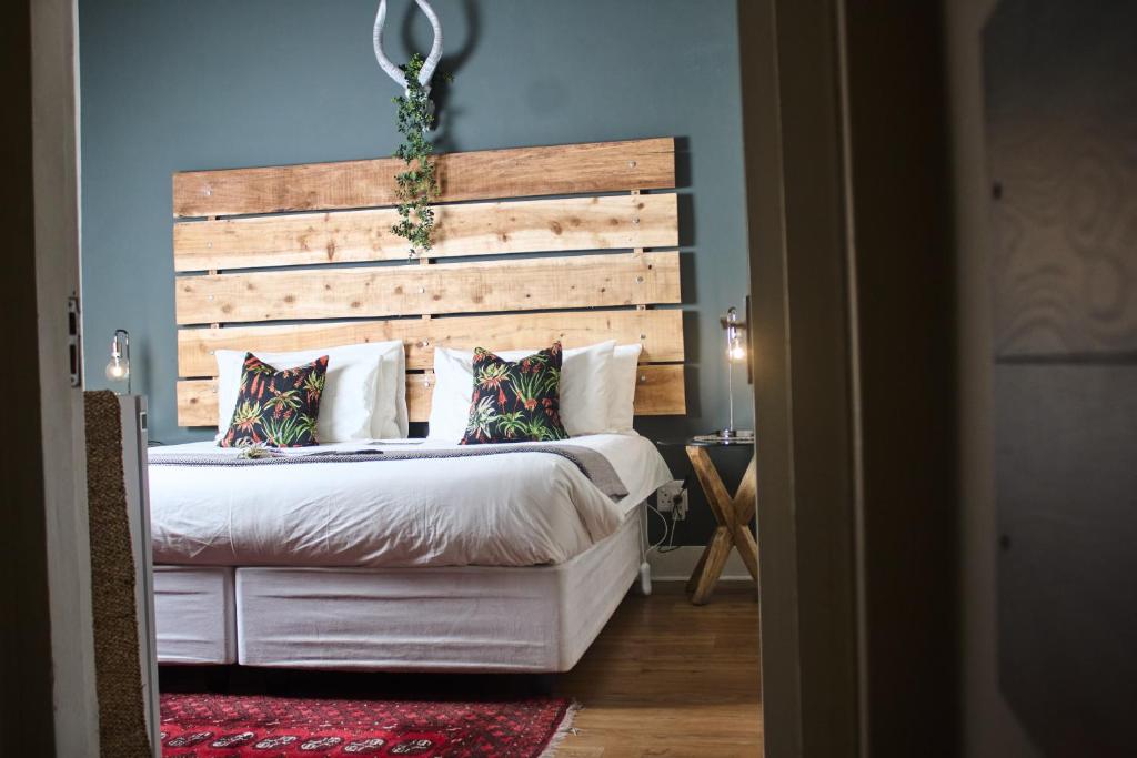 奥茨胡恩De Akker Guest House Oudtshoorn的一间卧室配有一张大床和木制床头板