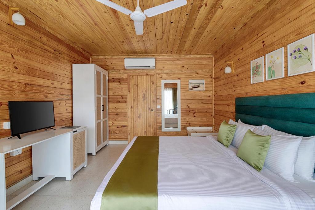 莫尔吉姆Aralea Beach Resort By Stone Wood, Morjim的一间带木墙的卧室和一张带电视的床