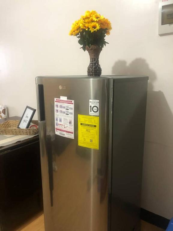 伊穆斯Amenadiel & CC - Imus Staycation的冰箱顶上带黄色花的花瓶