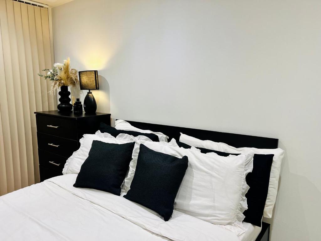 伦敦Luxury Modern Canary 1 bedroom Apartment的卧室配有白色的床和黑白色枕头
