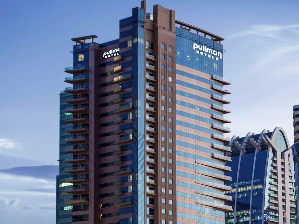 迪拜迪拜朱美拉湖塔楼普尔曼酒店的一座高大的建筑,旁边有一个标志