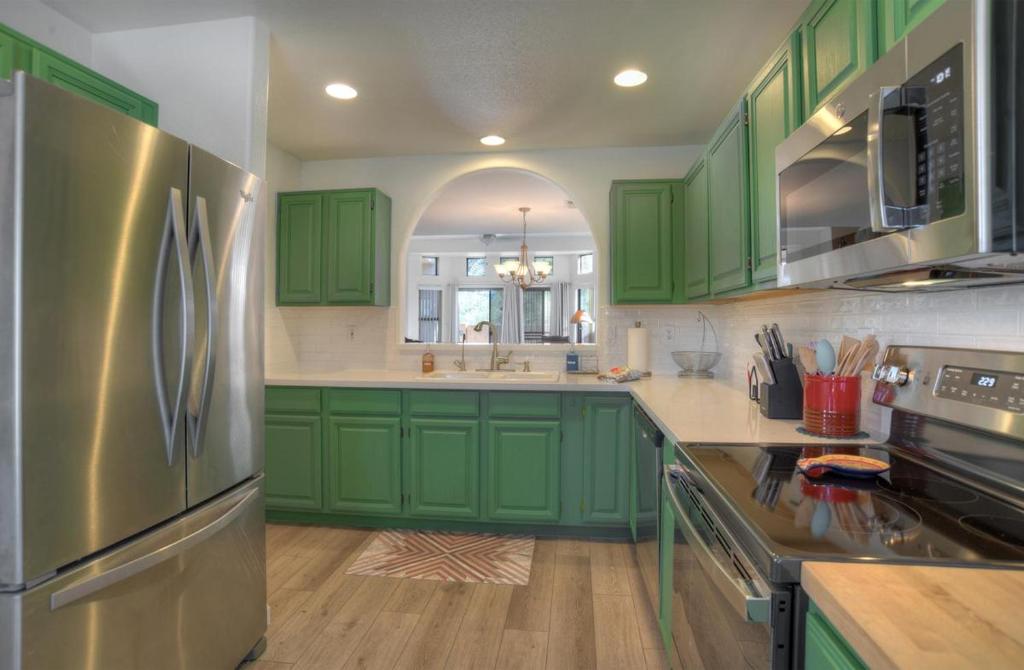 喷泉山Fountain Hills Bungalow West的厨房配有绿色橱柜和不锈钢冰箱