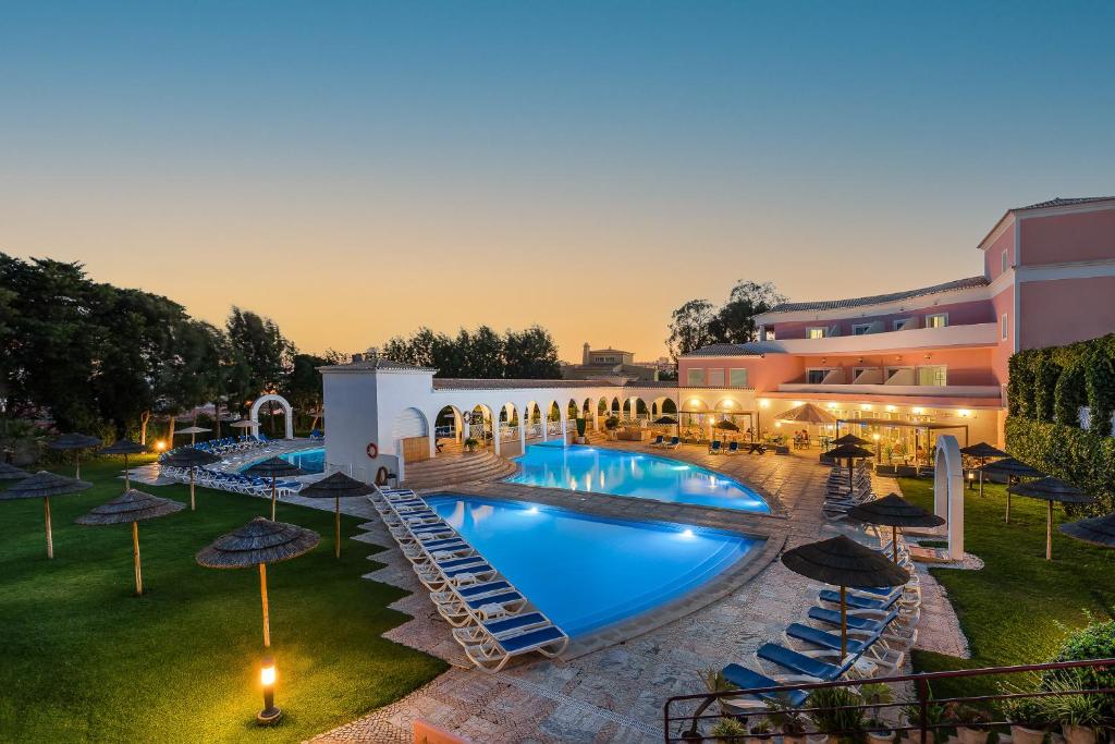 波尔蒂芒Clube Vilarosa的一张带游泳池和遮阳伞的酒店形象