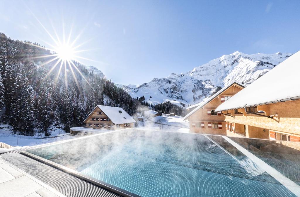 施勒肯Berghaus Schröcken - Hotel Apartments Spa的雪地中带游泳池的度假村