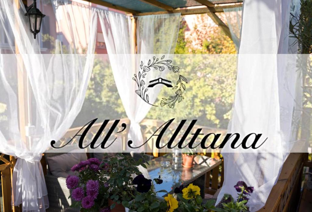 马格拉All’Altana b&b apartment的窗户,上面有白色窗帘和花朵