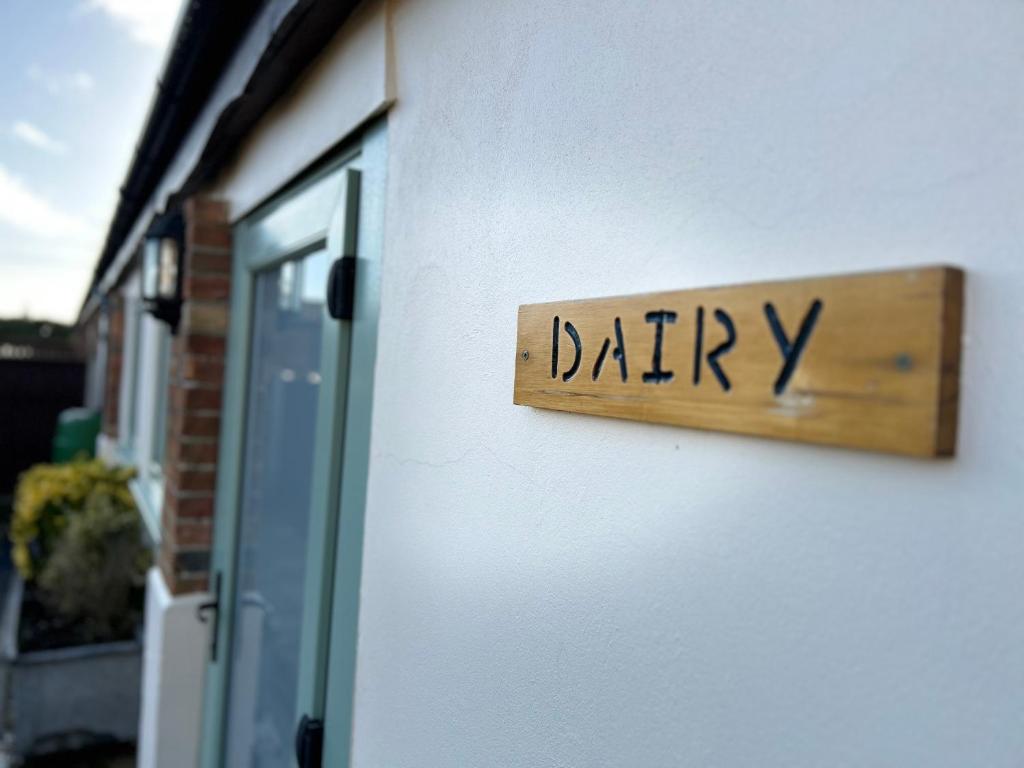 芬当The Dairy, Bramble Farm Cottages的建筑一侧的奶制品标志