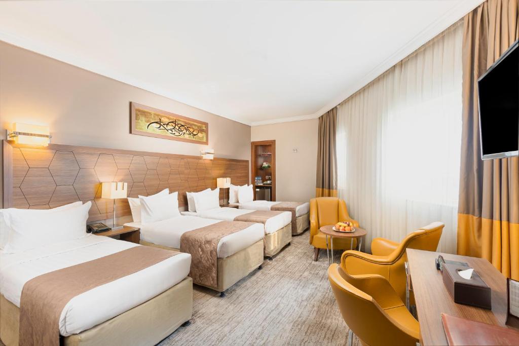麦地那Diwan Rose Hotel的酒店客房设有三张床和电视。