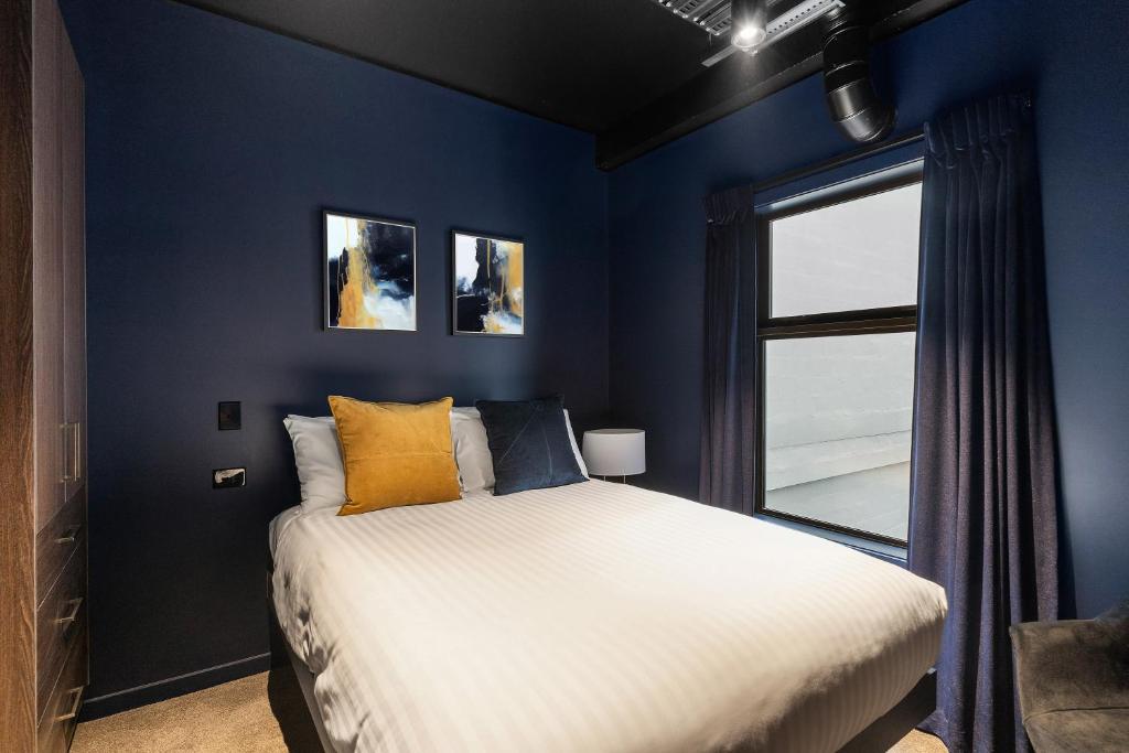 奥克兰Abstract Hotel & Residences的蓝色的卧室设有床和窗户