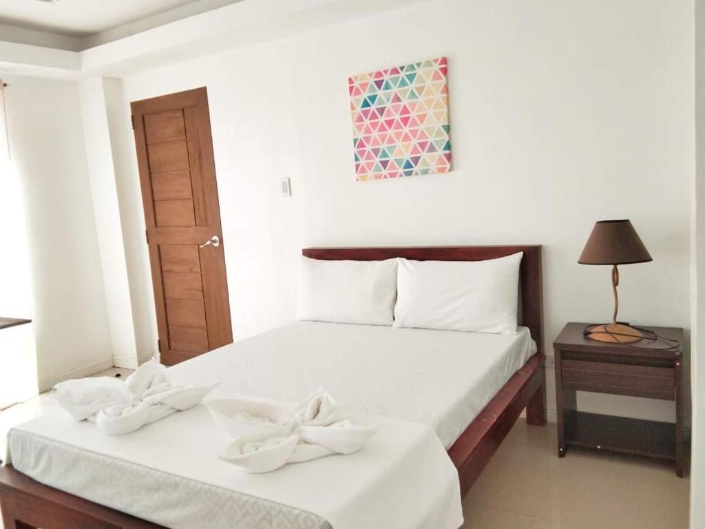 BanguedSorrento hotel resort santa ilocos sur的一间卧室配有两张带白色床单和弓的床铺