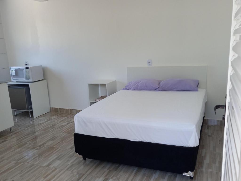 巴西利亚Apartamento Vila Telebrasilia的卧室配有白色的床和微波炉