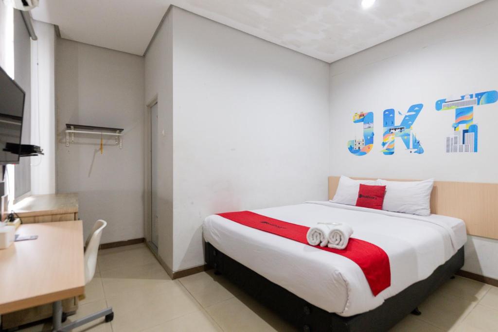 雅加达RedDoorz Plus Syariah near Mall Pondok Indah的一间卧室配有一张床,上面有两条毛巾