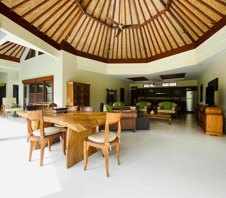沙努尔巴厘岛翡翠别墅酒店的一个带木桌和椅子的大客厅