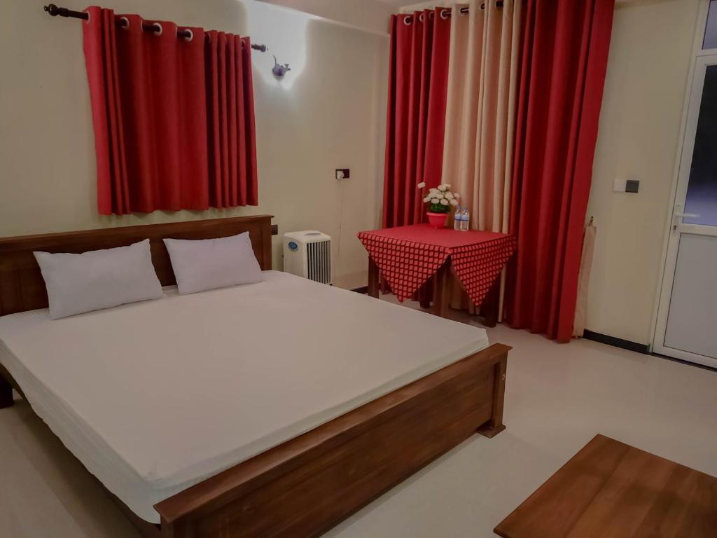 马拉维拉Eventide Beach Resort的一间卧室配有一张床、一张桌子和红色窗帘