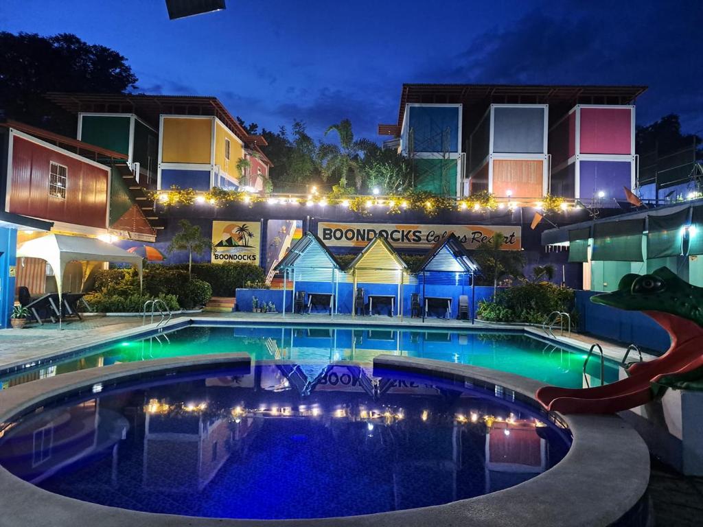 Dalumpinas OesteRedDoorz @ Boondocks Cabins Resort的一座游泳池,在晚上在建筑物前