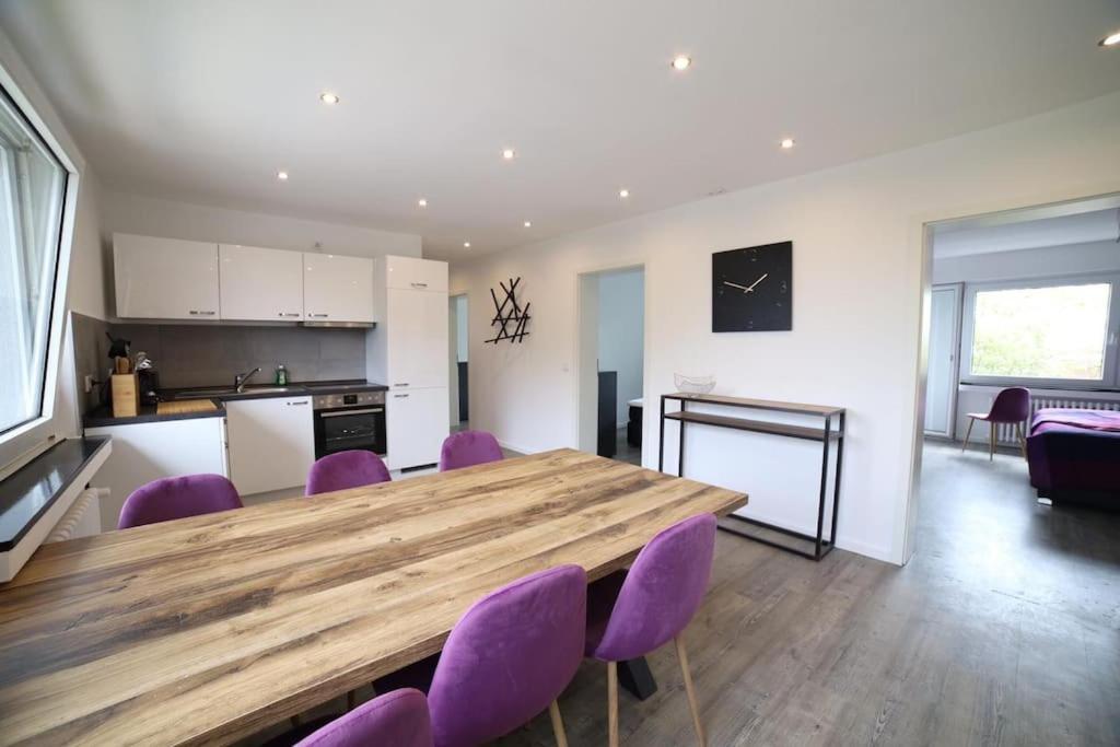 诺伊斯Designer-Apartment near Düsseldorf+Cologne (Apt.3)的厨房以及带木桌和紫色椅子的用餐室。