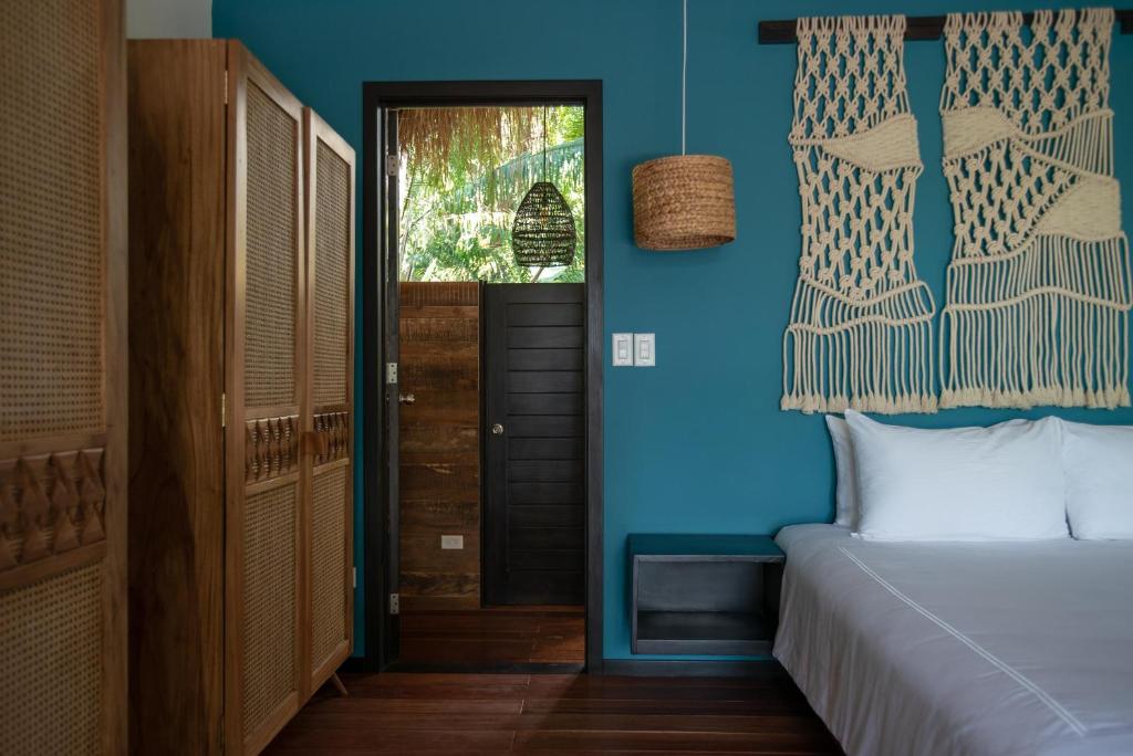 博卡奇卡The Resort at Isla Palenque Member of the Cayuga Collection的一间卧室设有一张床和蓝色的墙壁
