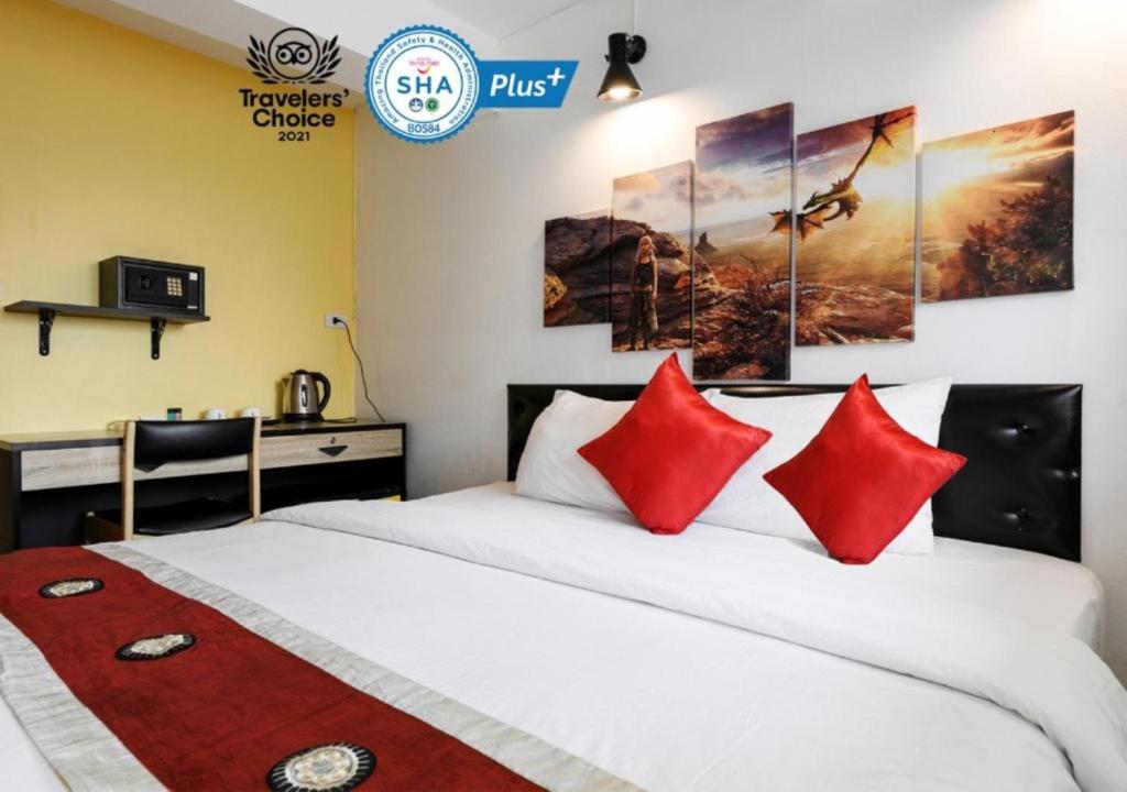 曼谷Khaosan Art Hotel - SHA Plus Certified的一间卧室配有一张带红色枕头的床和一张书桌