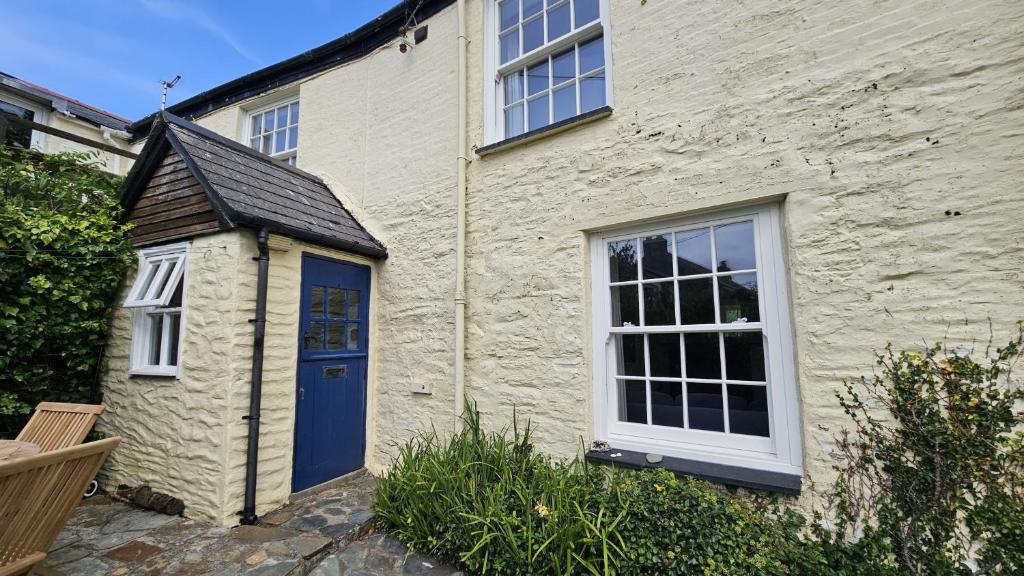圣莫斯Corner Cottage的白色砖屋,有蓝色的门