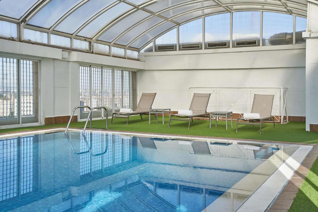瓦伦西亚NH瓦伦西亚中心酒店的一个带玻璃天花板的室内游泳池