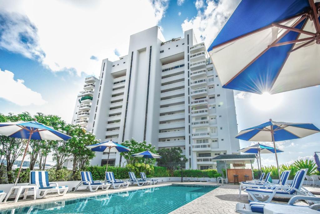 芭东海滩普吉岛-安达曼海难海景酒店 Phuket-Andaman Beach Seaview Hotel的大楼前的带椅子和遮阳伞的游泳池