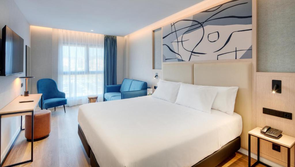 马拉加Sercotel Rosaleda Málaga的酒店客房设有一张白色大床和一张书桌