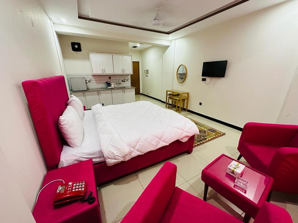 伊斯兰堡WE hotels Islamabad的一间设有床铺的客房和一间带红色椅子的厨房