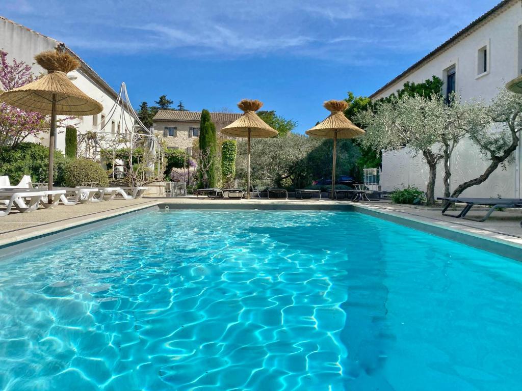 圣雷米普罗旺斯阳光Spa酒店的庭院里带遮阳伞的蓝色游泳池
