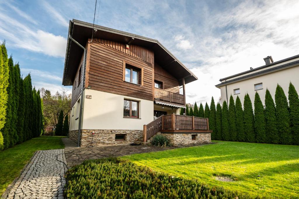 穆希纳Sokołówka的一座拥有木外墙和绿色庭院的房子