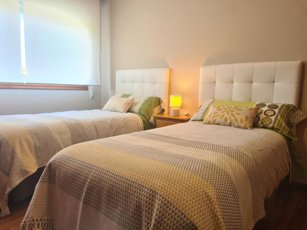 坎加斯德穆拉索Casa Campelo - APARTAMENTO Playa de Rodeira Cangas的一间卧室设有两张床和窗户。