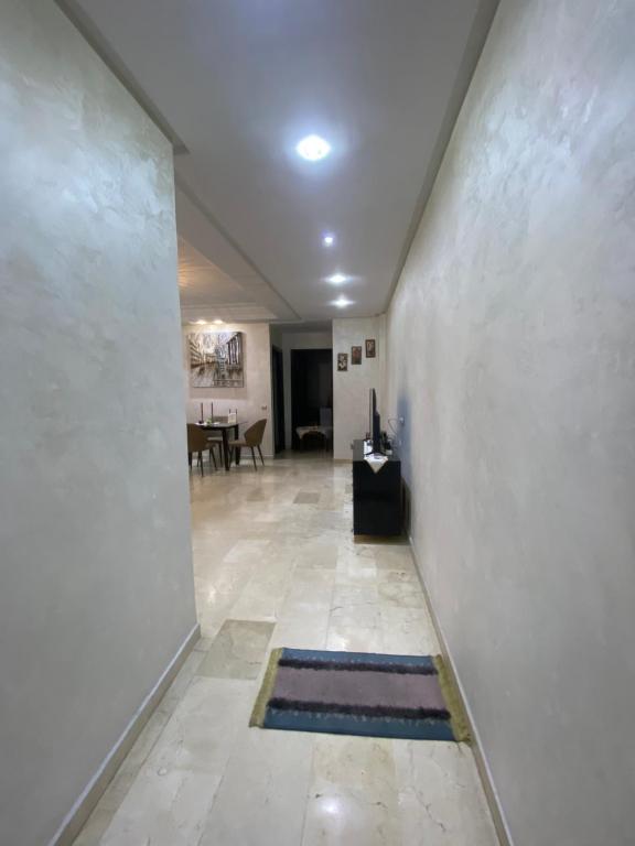 卡萨布兰卡Appartement de lux的一条带白色墙壁的走廊和一间带桌子的房间