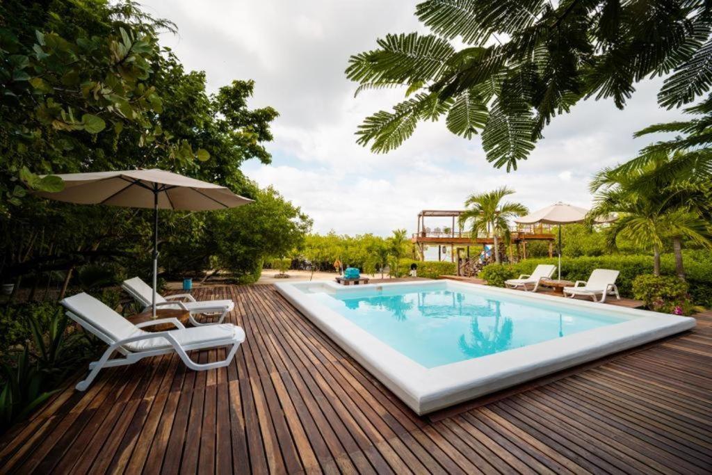 巴尔Hotel Playa Scondida的木制甲板上配有椅子和遮阳伞的游泳池
