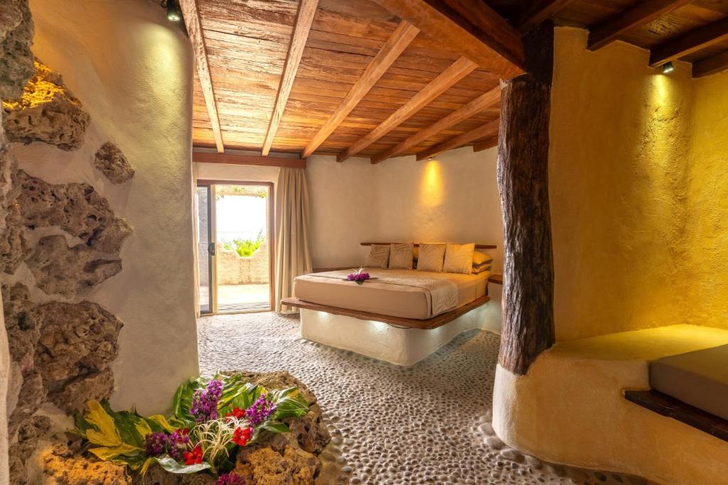 塔纳岛Rockwater Resort的一间卧室设有一张床和石墙